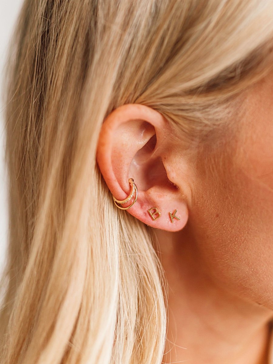 Gold initial studs paired with diamond and gold ear cuff on model ear