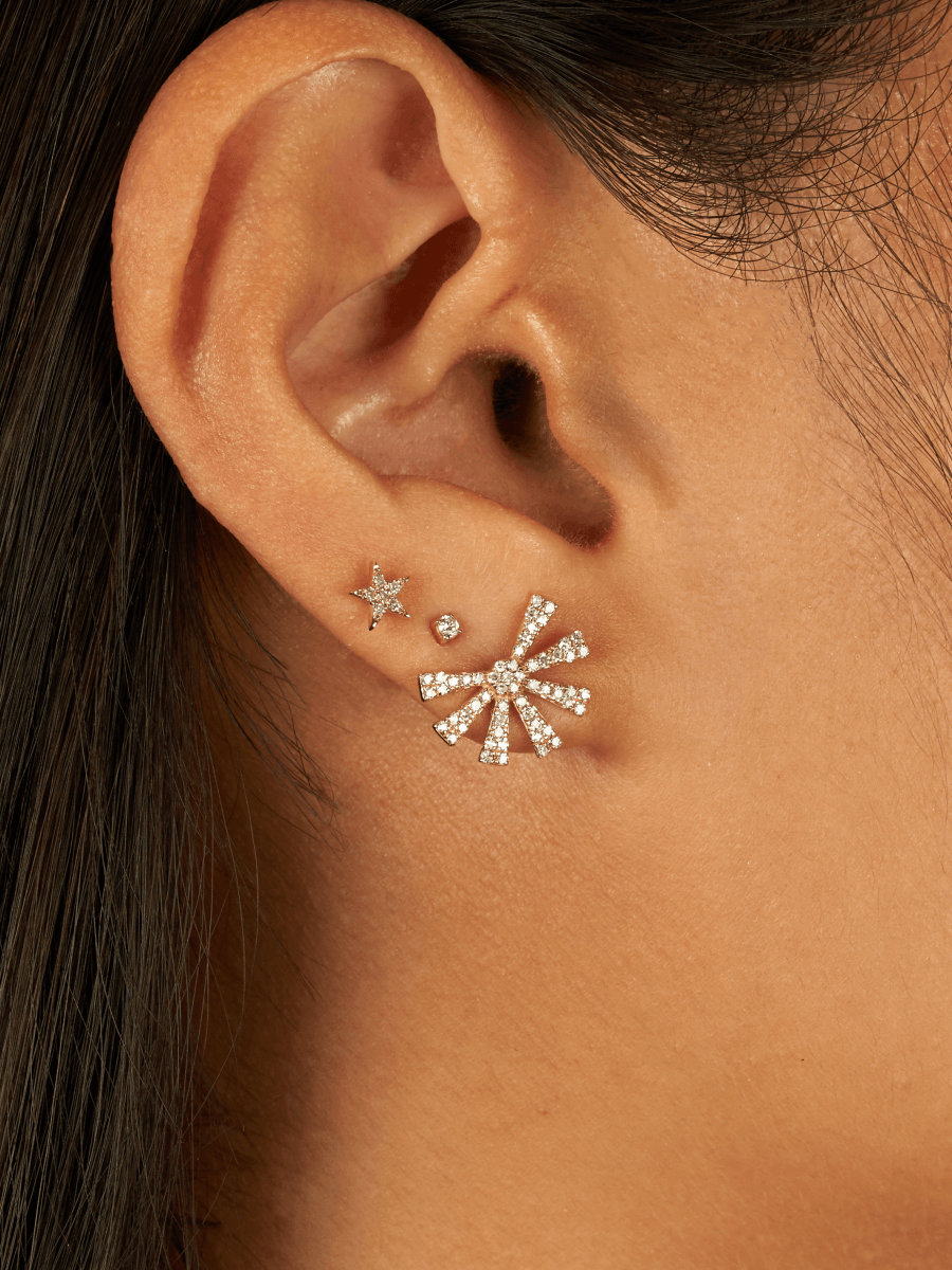 Mini gold star earring paired with diamond stud and diamond starburst stud on model ear