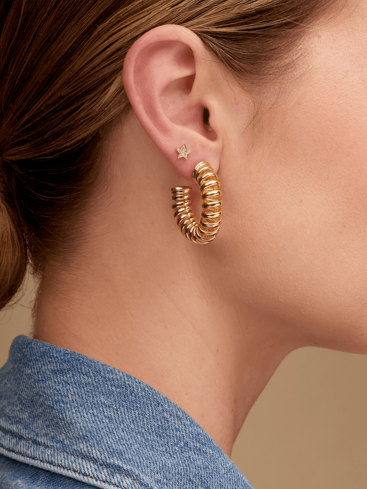 Gold star earring paired with large gold coil hoop