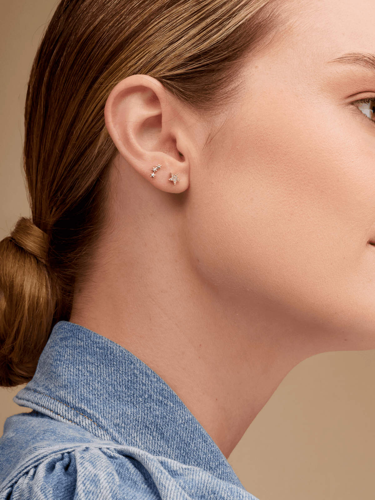 Gold star earring paired with star trio stud on model ear