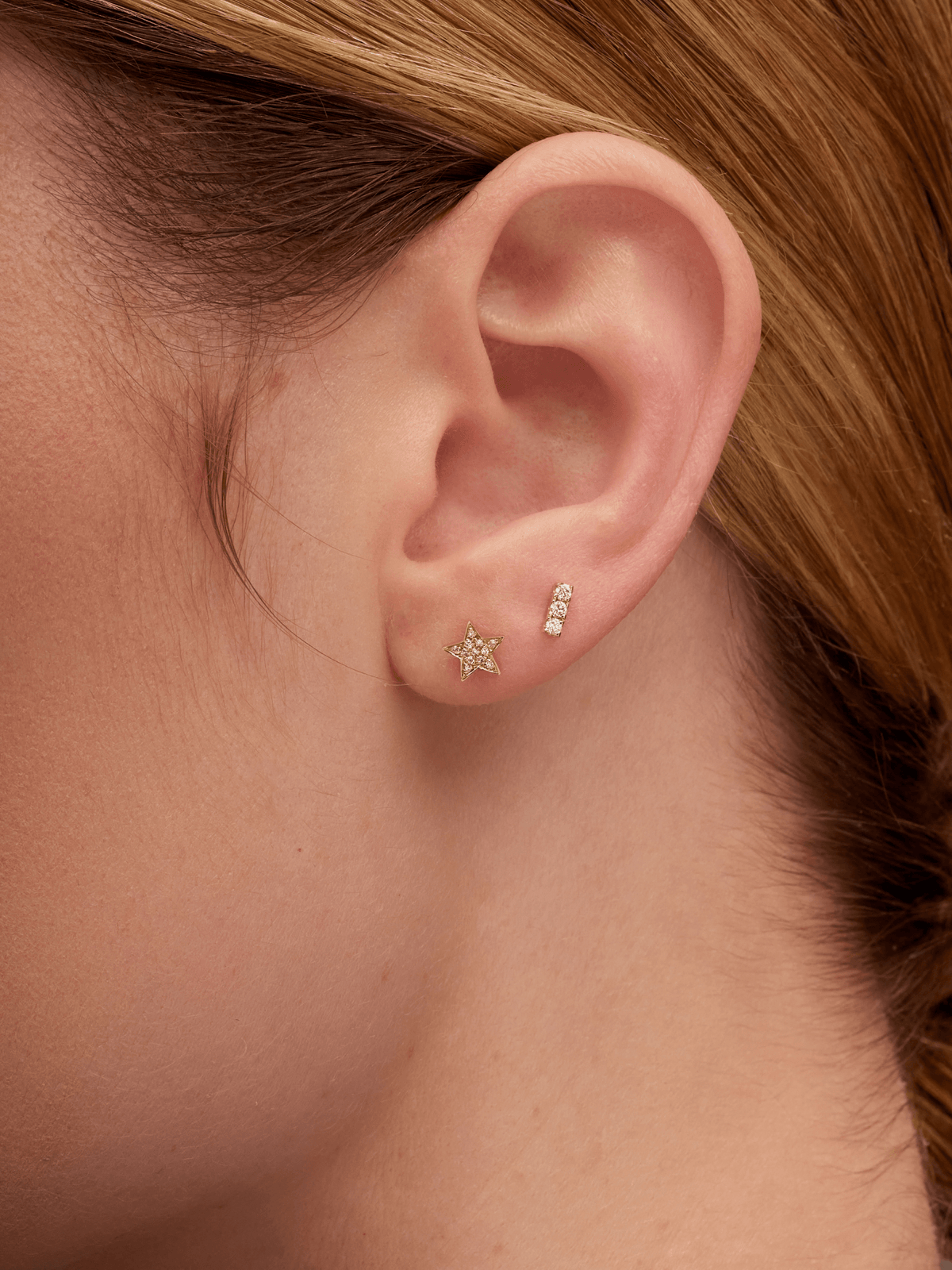 Mini gold star earring paired with diamond bar stud on model ear