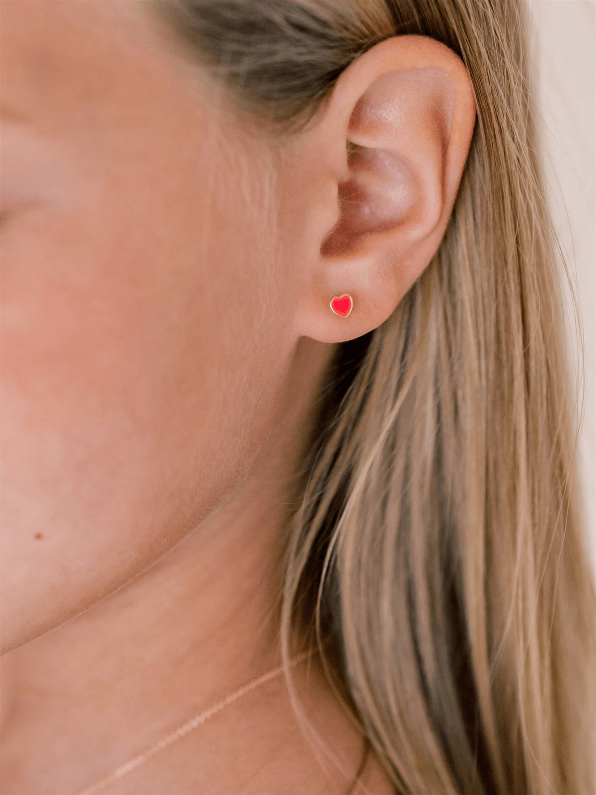 Enamel stud earring neon pink heart on model ear