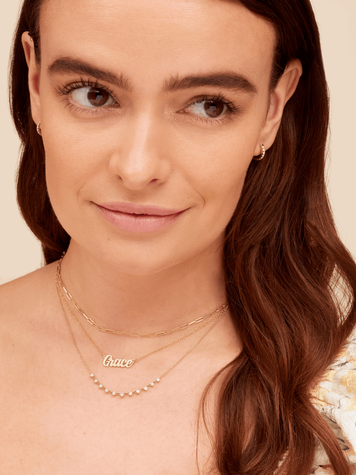Gold script name necklace layered with gold paperclip chain and graduated diamond layering necklace
