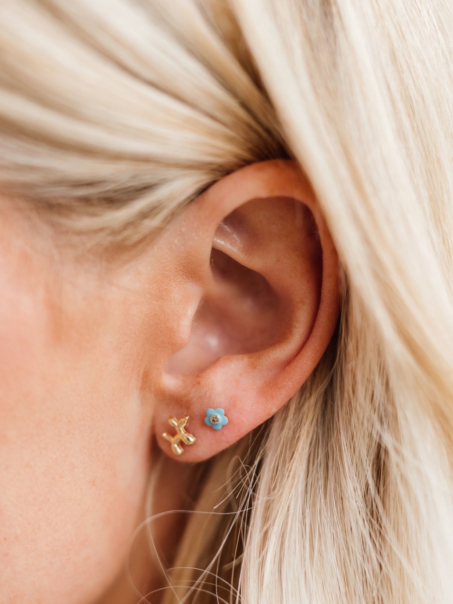 Kid gold puppy earring paired with turquoise flower stud on model ear