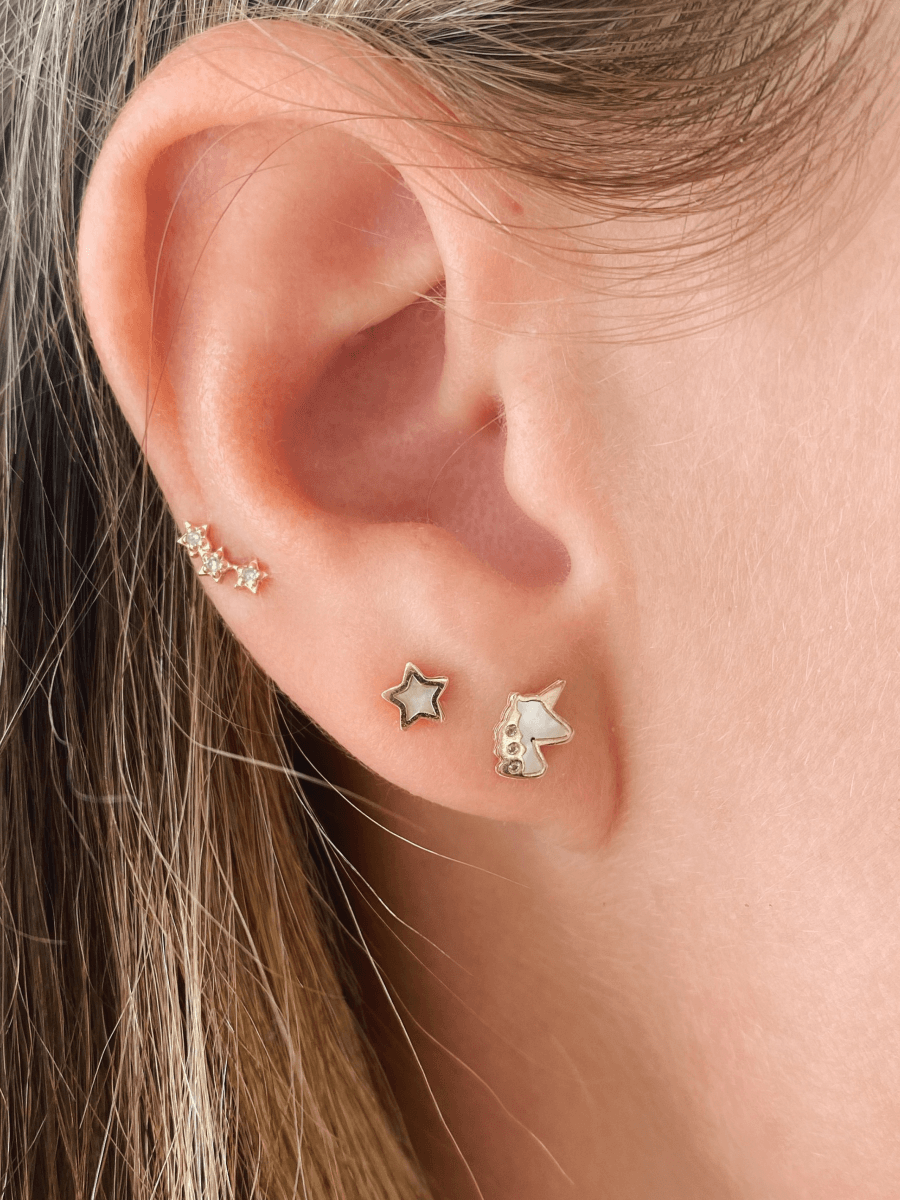 Unicorn stud earring paired with single star stud and trio star stud on model ear
