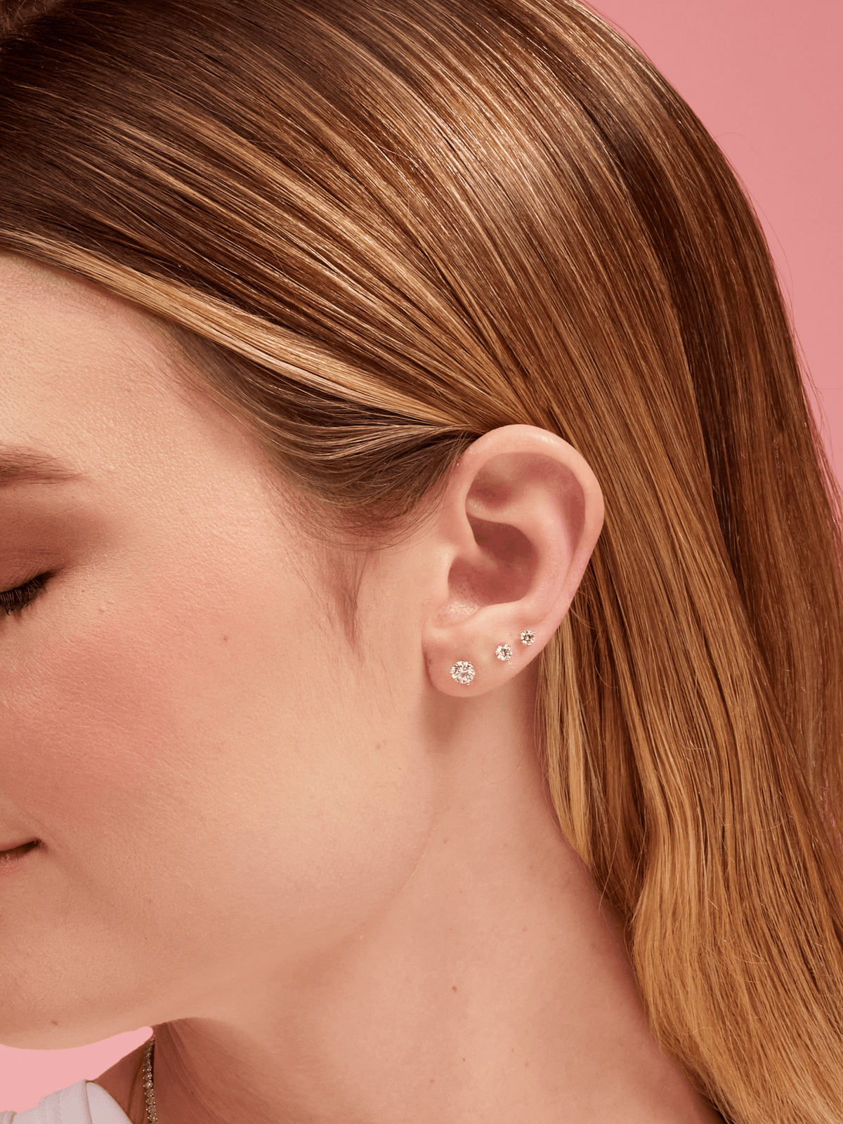 Three diamond stud earrings in different sizes on model ear