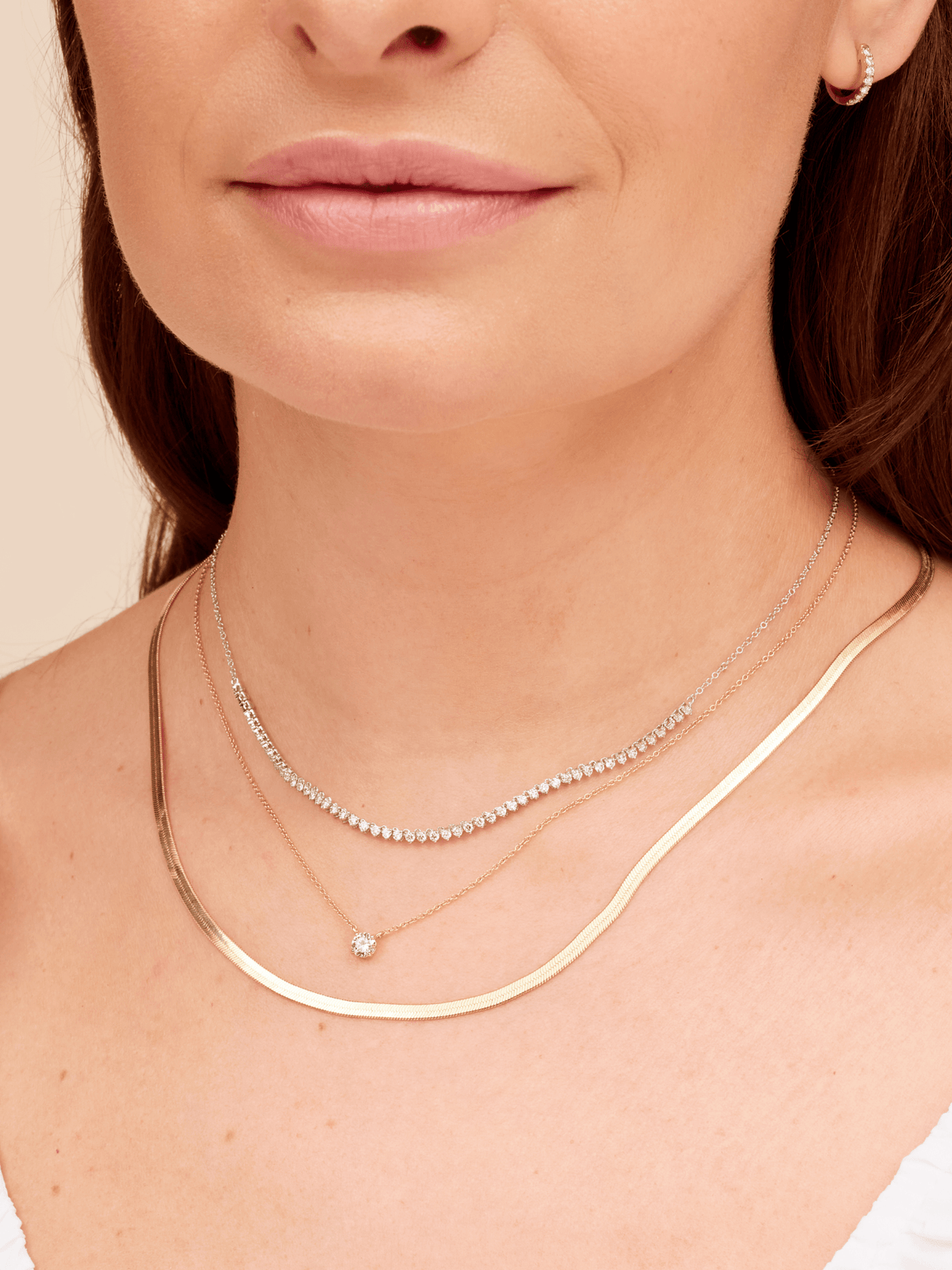 Diamond tennis chain necklace in 14K white gold layered with herringbone snake gold chain necklace and thin gold chain with single diamond
