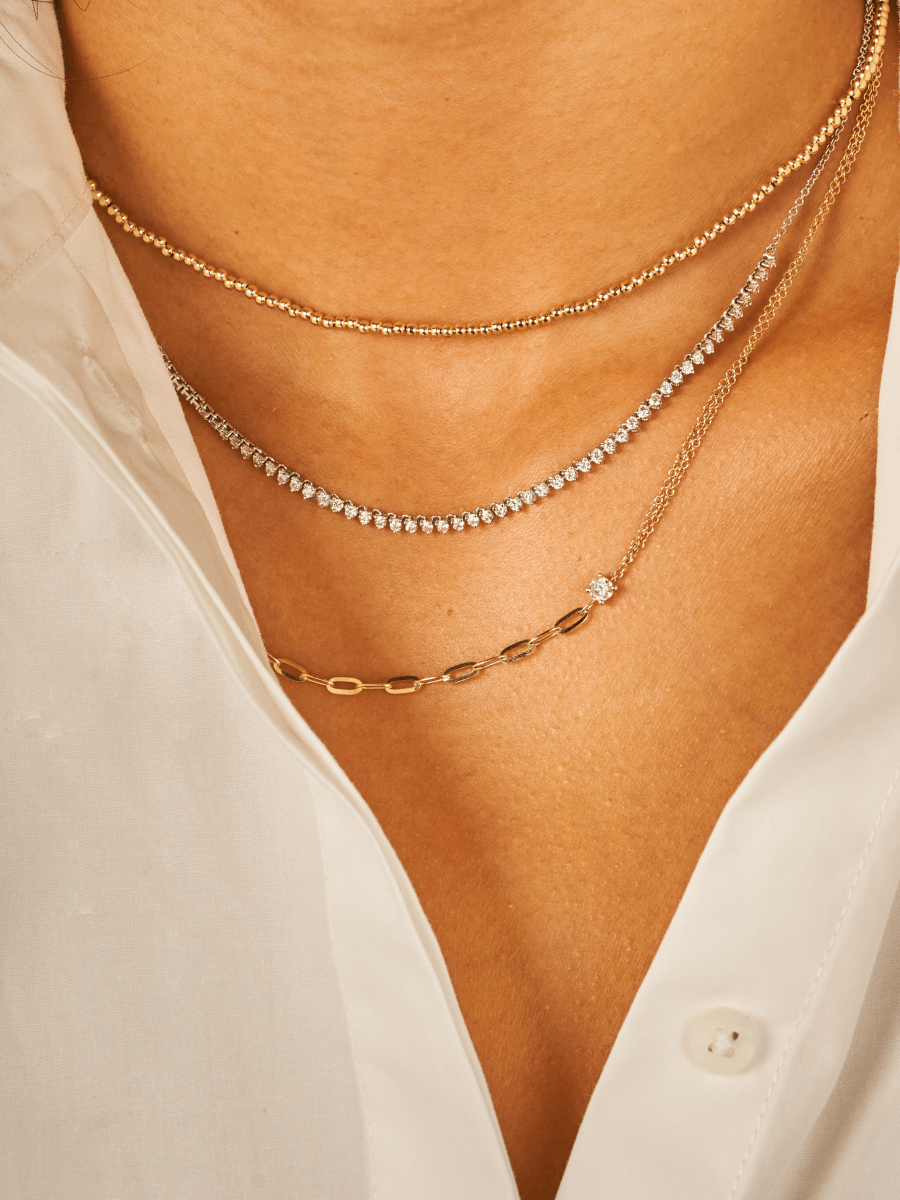 Diamond tennis chain necklace in 14K white gold layered with thin gold beaded choker and mixed chain necklace with diamond