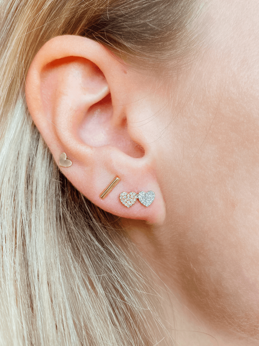 Diamond heart earring paired with gold bar stud and gold heart stud on model ear