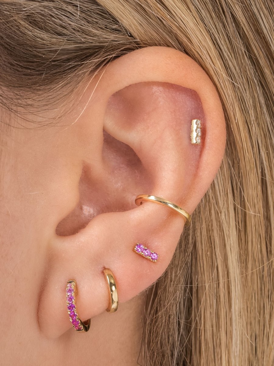Pink ombre huggie paired with gold huggie, pink sapphire bar stud, gold ear cuff, and diamond bar stud on model ear