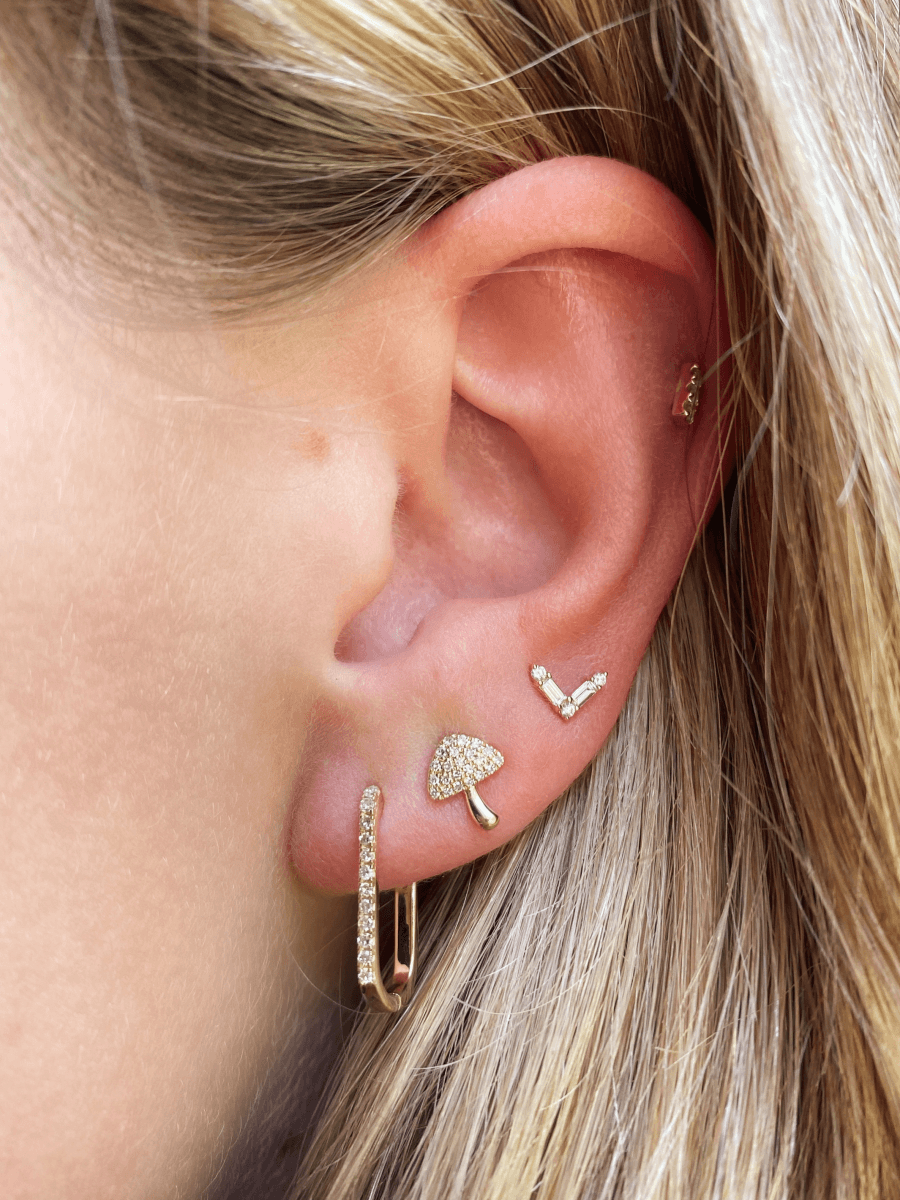 Diamond paperclip earring paired with diamond mushroom stud, diamond chevron earring, and diamond bar stud on model ear