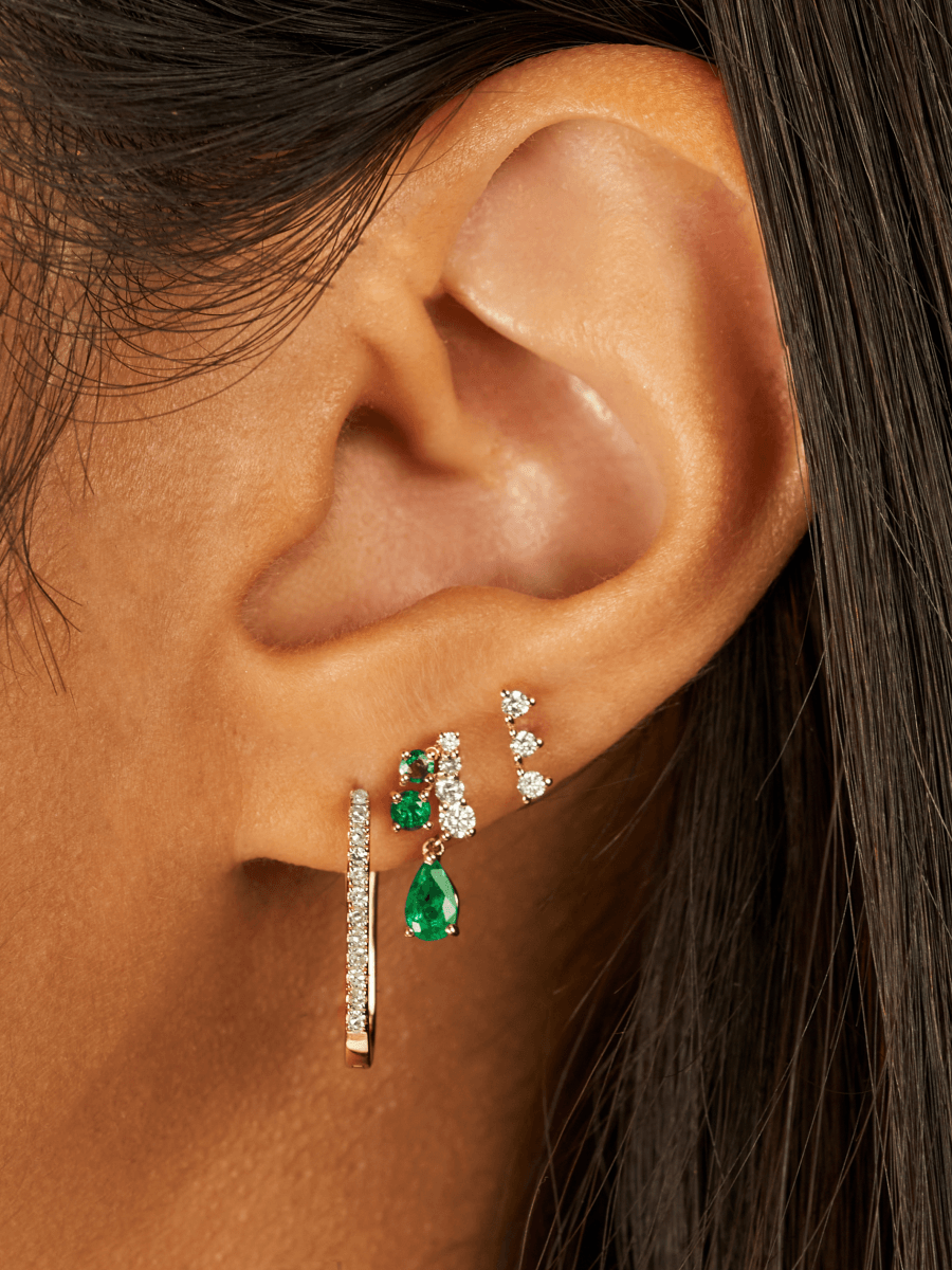 Diamond Paperclip Huggie in Yellow Gold in First Hole of Ear with Diamond and Emerald Dangle Earring in Second Hole and Three Diamond Bar Stud in Third Hole of Ear