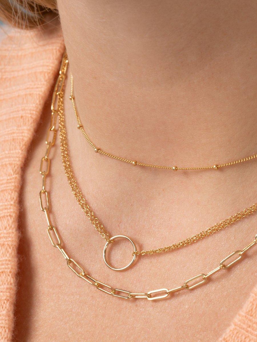 Paperclip chain necklace layered with gold circle necklace and gold chain with small gold beads