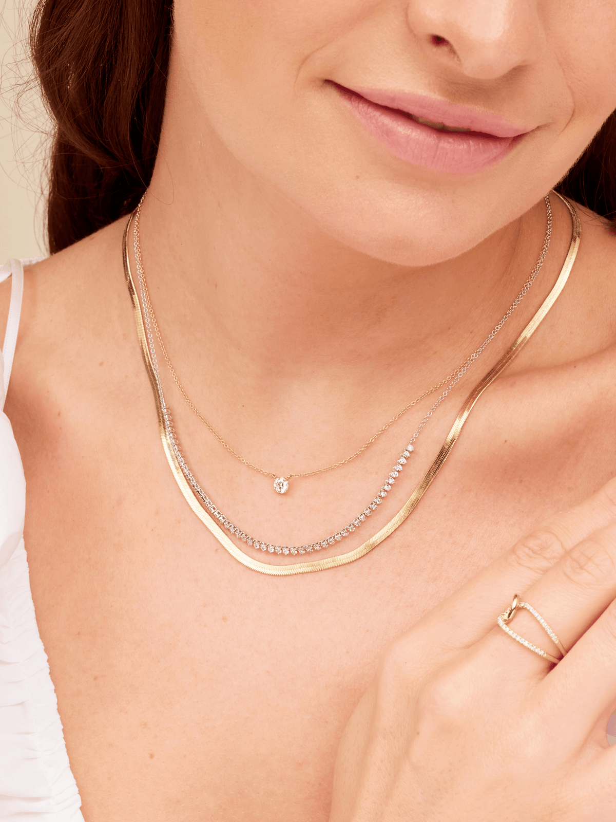 Round diamond pendant necklace layered with diamond tennis chain necklace and gold snake chain