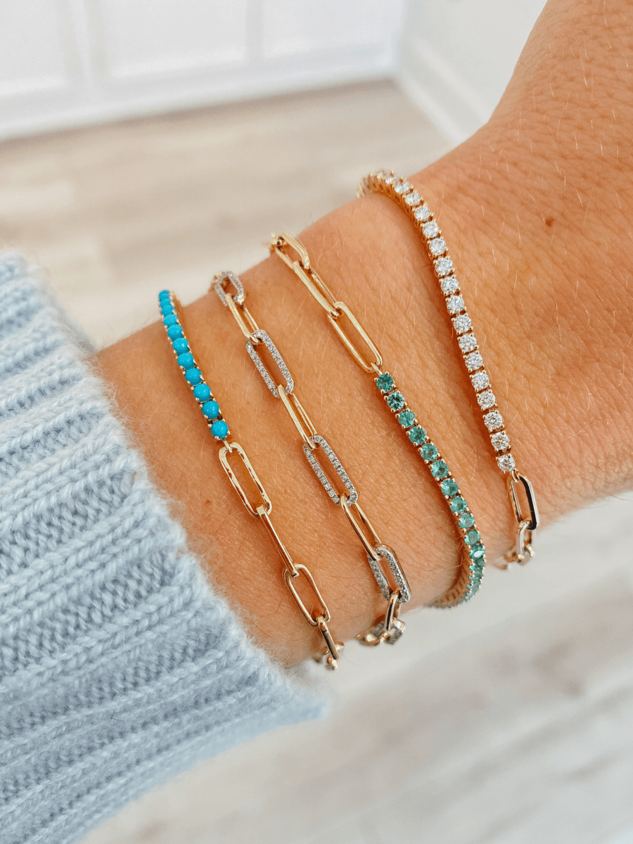 Half turquoise half gold paperclip chain bracelet layered with diamond and gold paperclip chain bracelet, half emerald tennis bracelet half gold paperclip chain, and half diamond half gold paperclip chain tennis bracelet