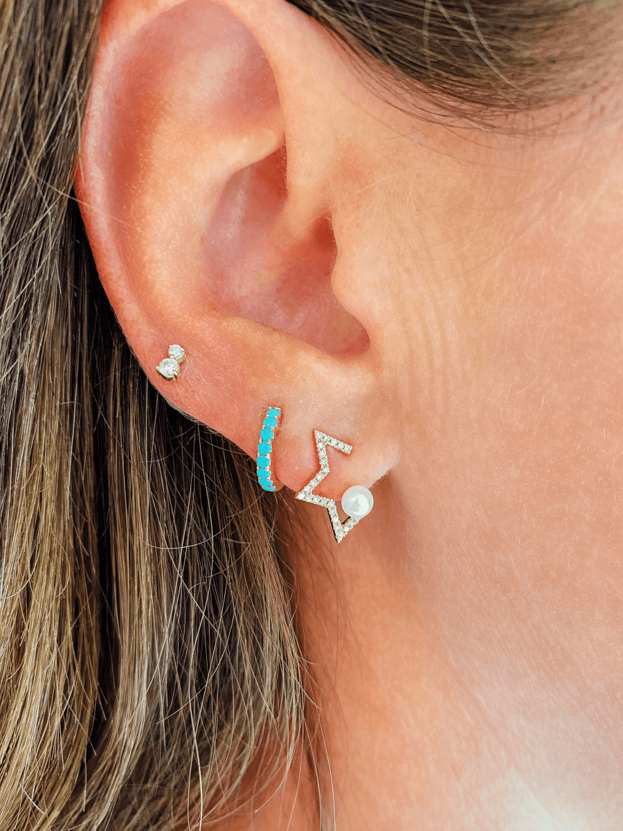 Pearl star earring with diamonds paired with turquoise huggie and double diamond stud earring on model ear