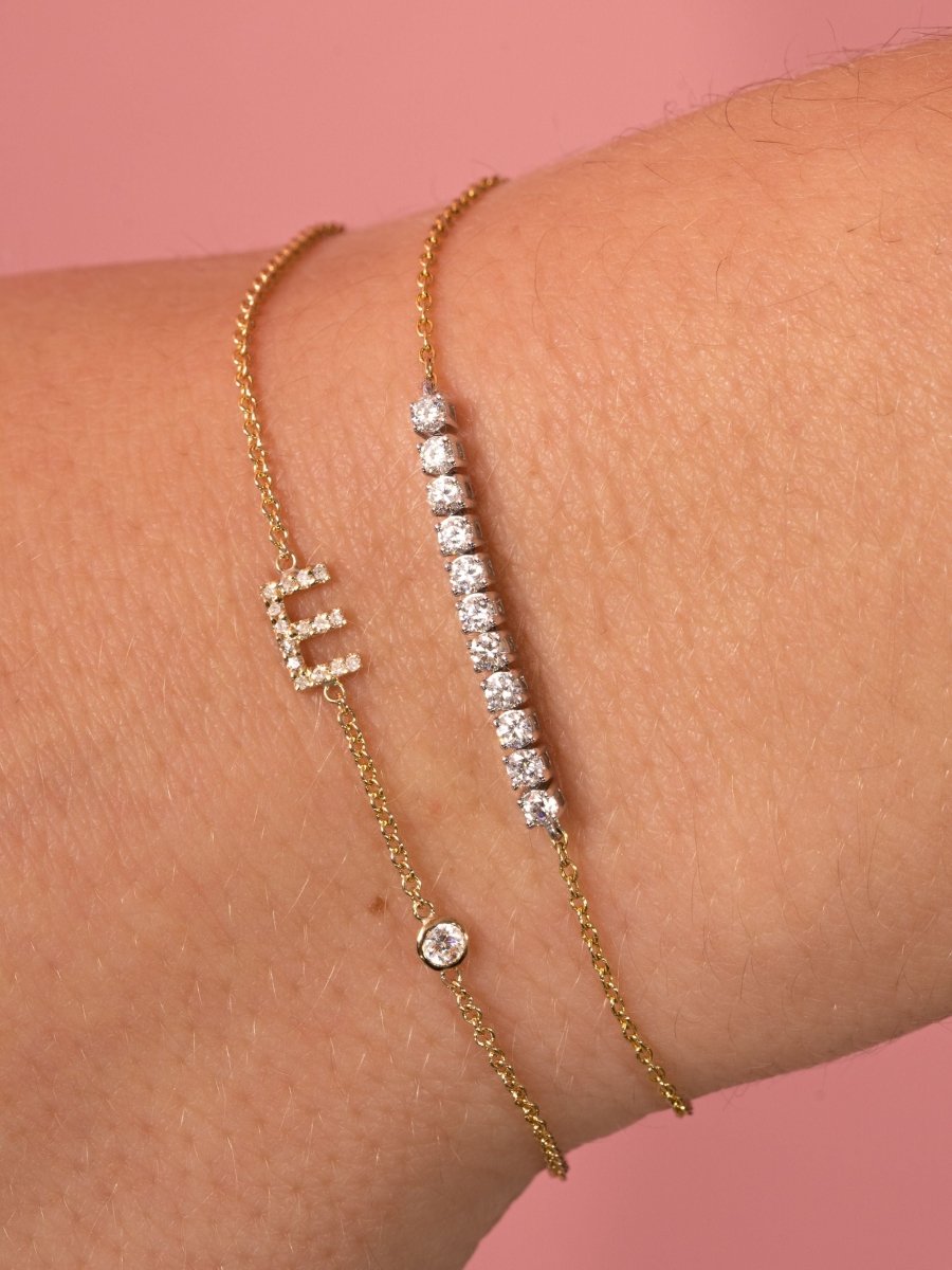 Dainty gold chain bracelet with pave diamond initial charm and single round diamond paired with diamond tennis gold chain bracelet