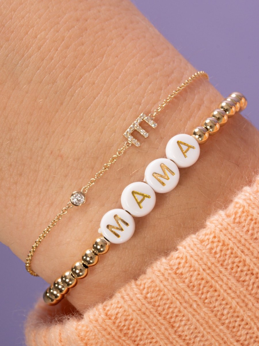 Dainty gold chain bracelet with pave dimaond initial charm and single, round diamond paired with customized gold beaded stretchy bracelet 