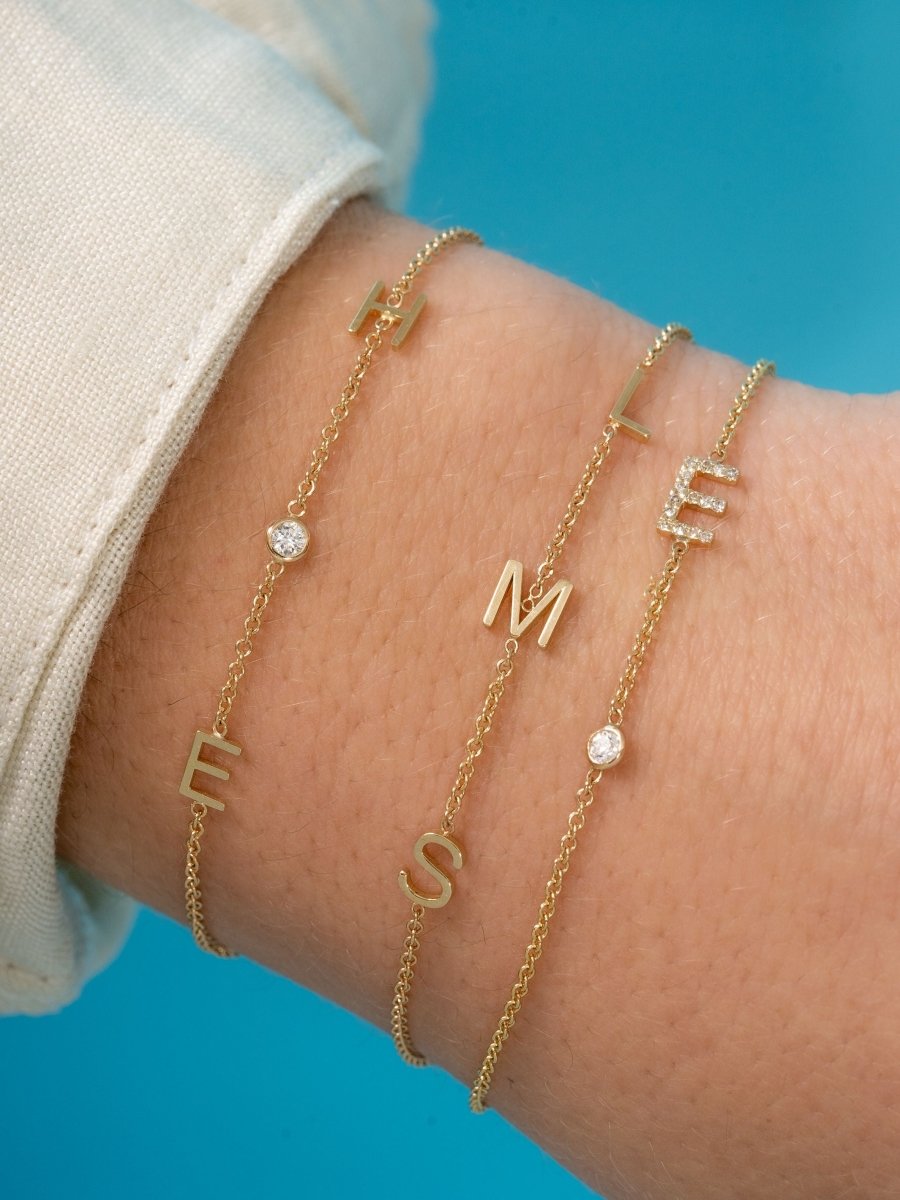 Dainty gold chain bracelet with single diamond initial and single diamond layered with dainty gold chain bracelet with three initial letters and dainty gold chain bracelet with two initial letters and single diamond