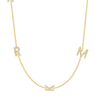 Four dainty diamond initial charms on simple gold chain on white background