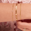 Dainty gold chain bracelet with two gold initial letters and singular diamond layered with small gold chain bracelet and valentino gold chain bracelet 