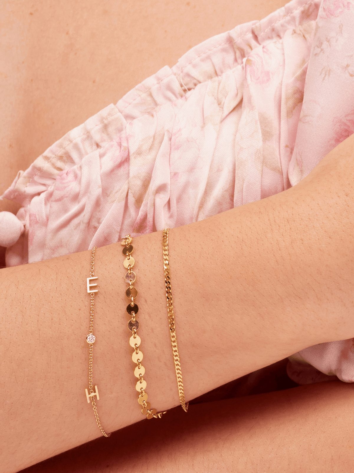 Dainty gold chain bracelet with two gold initial letters and singular diamond layered with small gold chain bracelet and valentino gold chain bracelet 