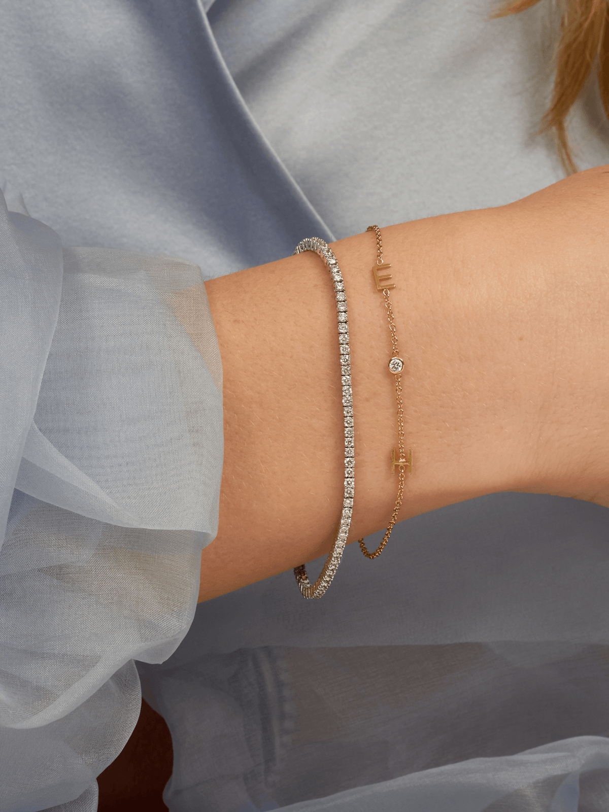 Dainty gold chain bracelet with two initials and single diamond layered with diamond tennis bracelet