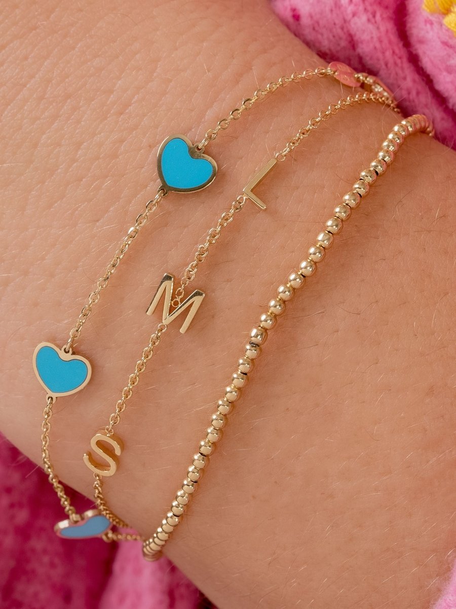 Dainty gold chain bracelet with three initials layered with gold beaded bracelet and bracelet with turquoise hearts on simple gold chain