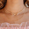 Small gold beaded necklace with small heart charm layered with dainty gold chain with two initial letters and simple gold paperclip necklace