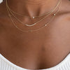 Dainty gold chain with three initial letters and two small diamonds layered with chasing diamond gold chain necklace and single diamond set on dainty gold chain