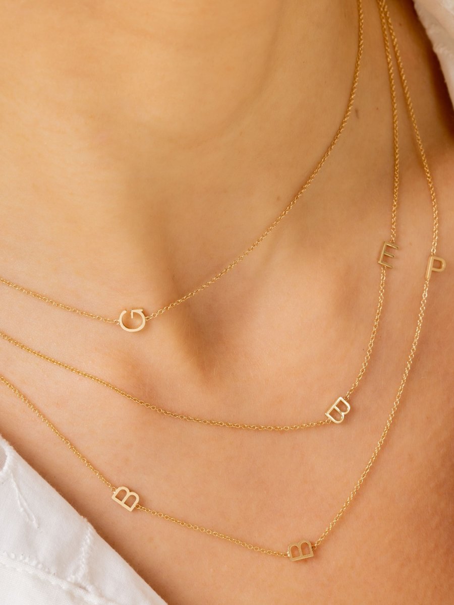Dainty gold chain with single initial letter layered with dainty gold chain with two initial letters and another dainty gold chain with three initial letters