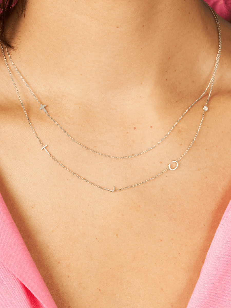 Dainty white gold chain necklace with three initials and single diamond layered with white gold chain necklace with cross