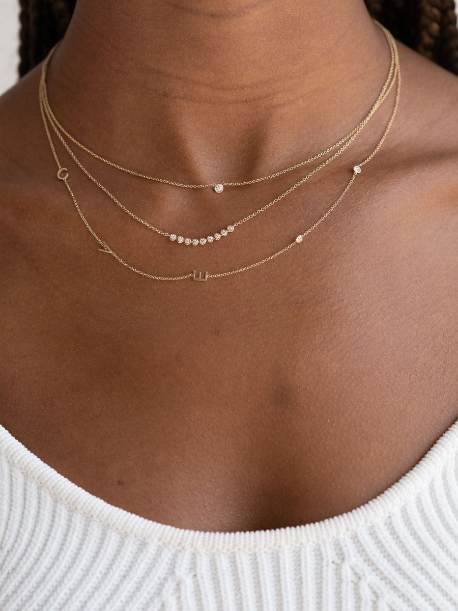 Dainty gold chain with three initial letters and two small diamonds layered with chasing diamond gold chain necklace and single diamond set on dainty gold chain