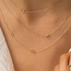 Dainty gold chain with single initial letter layered with two other dainty gold chains with two initial letters