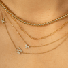 3 stone diamond necklace layered with gold beaded choker, gold paperclip necklace, and diamond initial necklace